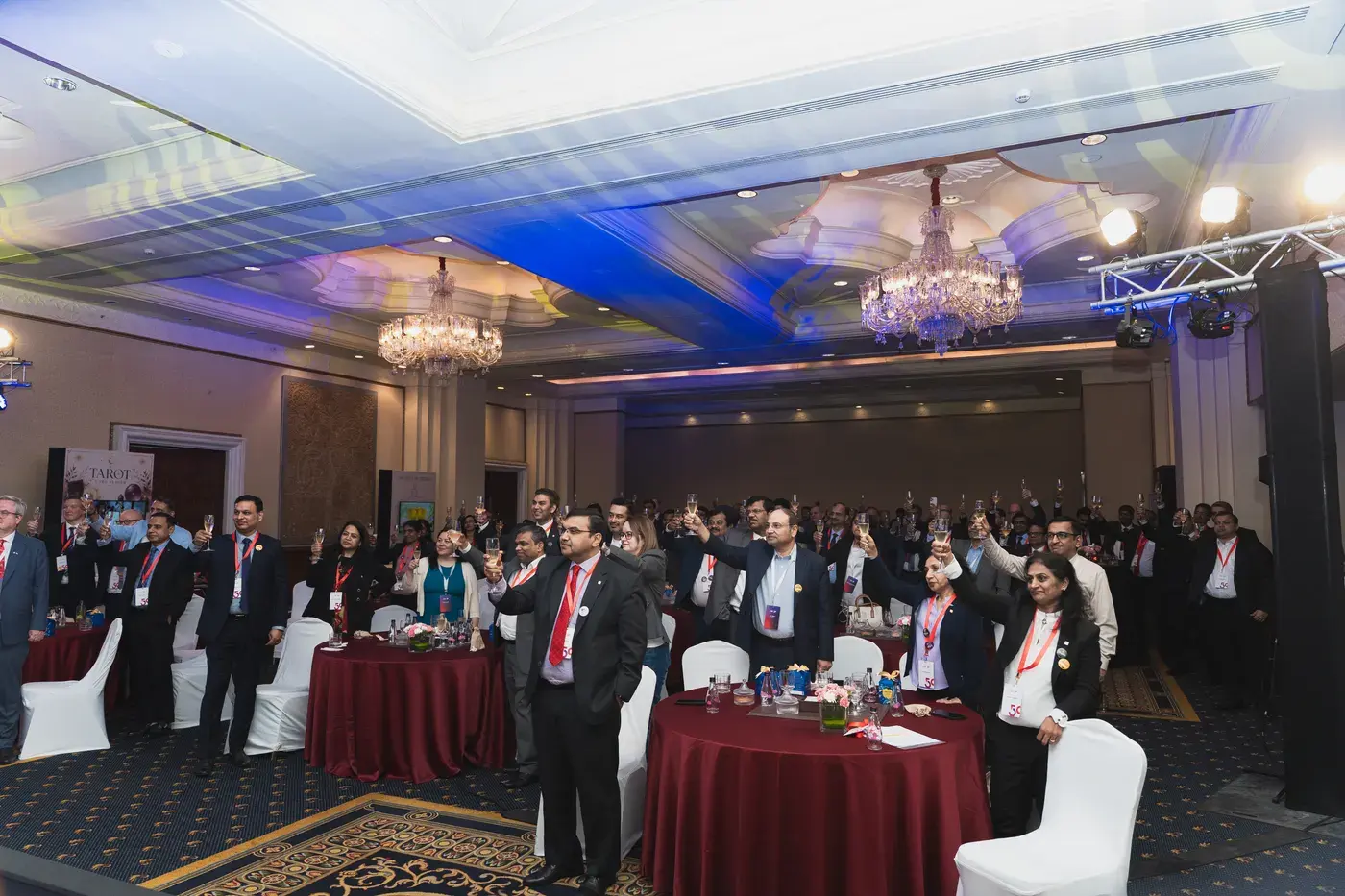 A banquet hall of guests applauding under chandeliers at an awards night