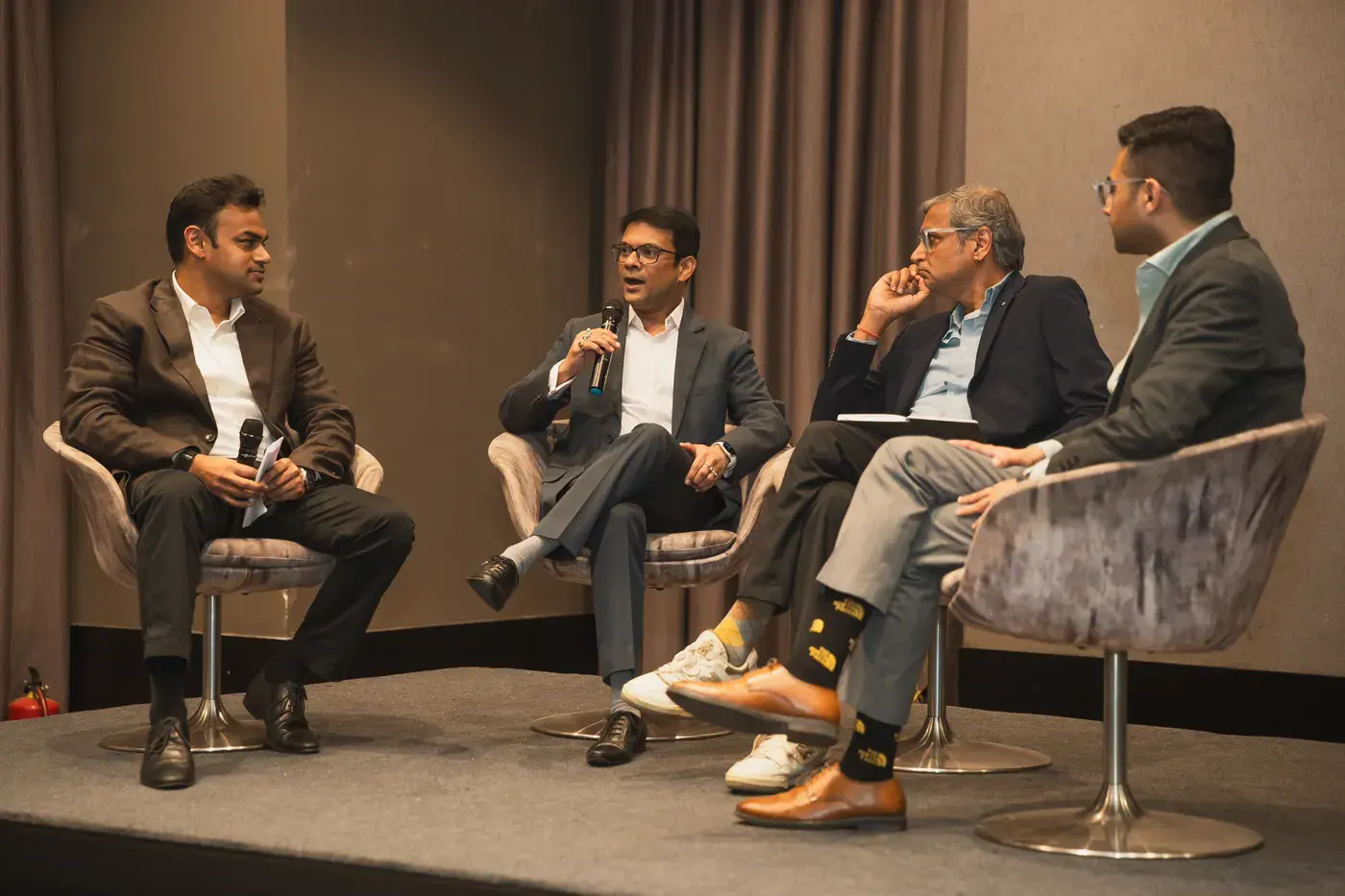 Four panellists mid-discussion in armchairs on a conference stage