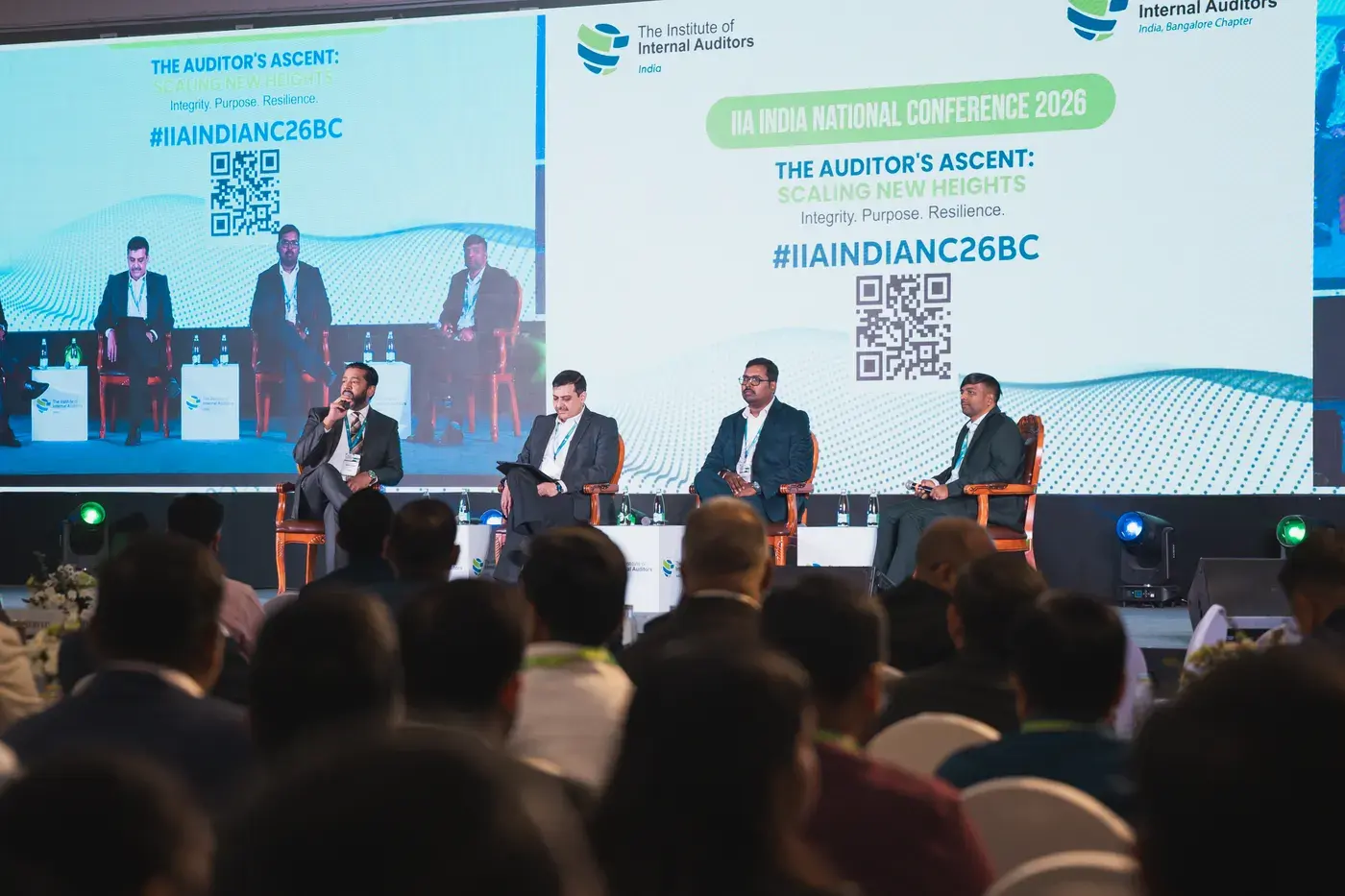 A panel on stage seen over the heads of a packed national conference audience
