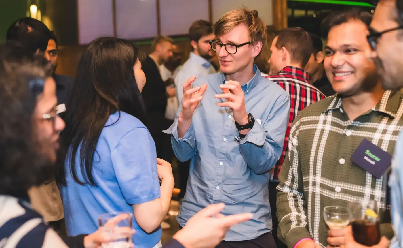 Colleagues talking and laughing over drinks at an office networking evening
