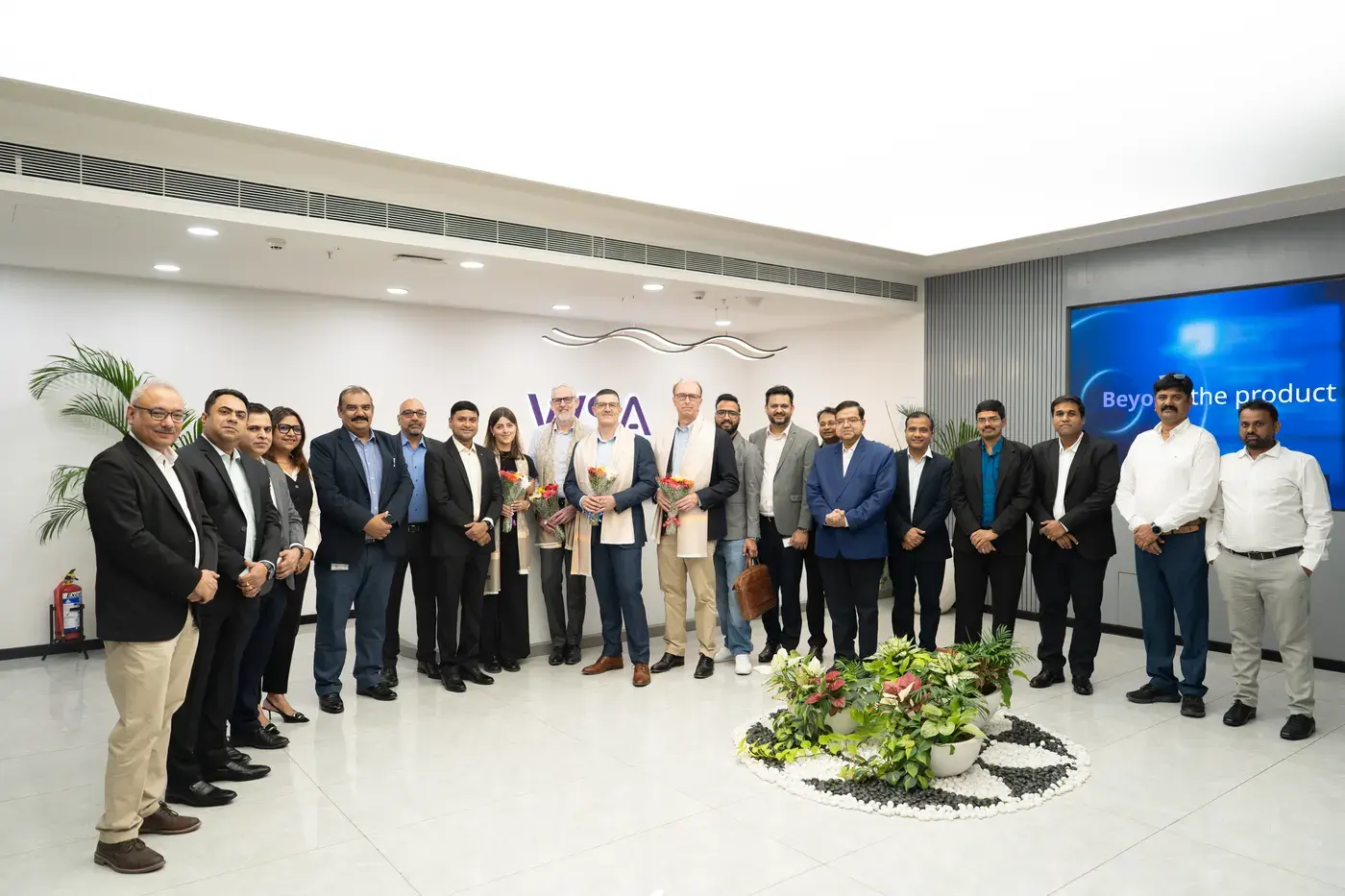 A full team lined up for a group photograph in a bright office atrium