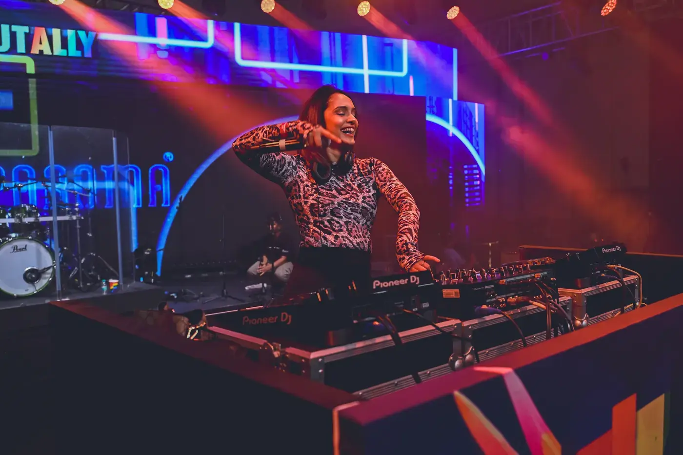 A DJ performing behind the decks under stage lighting
