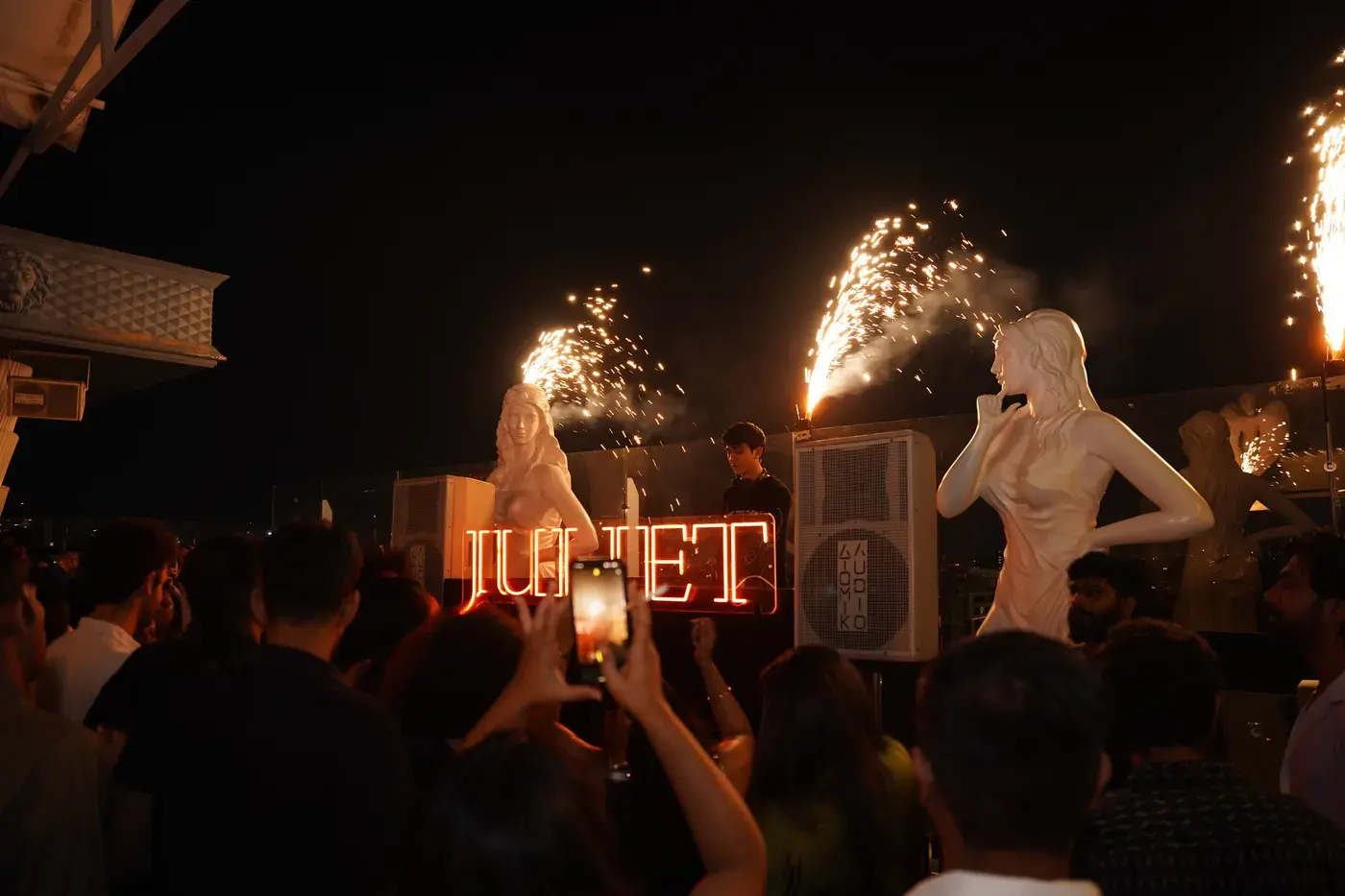 Sparklers firing above a crowd at an outdoor evening party
