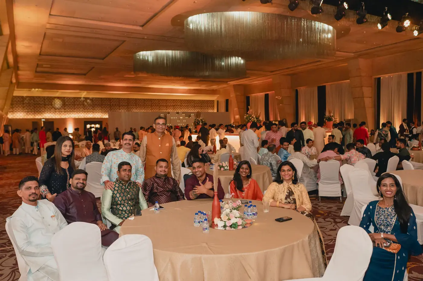 Guests seated at round tables in a chandelier-lit banquet hall